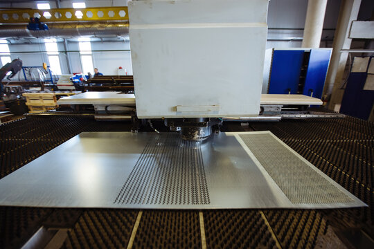 CNC punching and nibbling machine and perforated steel sheet, close up