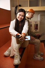 Cheerful woman with smartphone and busy guy with laptop