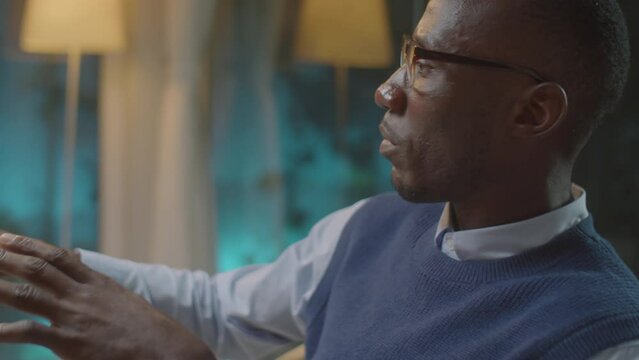 Medium close up shot of African American psychologist giving advice to patient during therapy session in his office