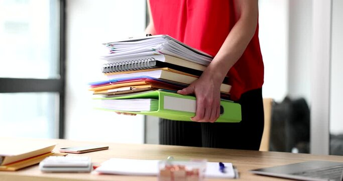 Female hands of trainee secretary hold stack of folders and documents. Overtime work time management and internship in company