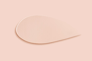 The texture of a smear of a light foundation on a beige background.