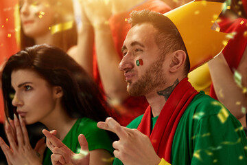 Portugal football fans emotionally watching match, game at stadium, supporting and cheering up team during tense moment. Concept of sport, competition, championship, emotions, hobby and entertainment