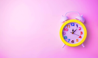 Bright alarm clock with a colored dial on a plain pink background.