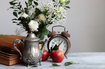 Vintage phone, rusty alarm clock, red apple gypsophila flowers on a desk. White background with copy space. Retro objects still life photo. 
