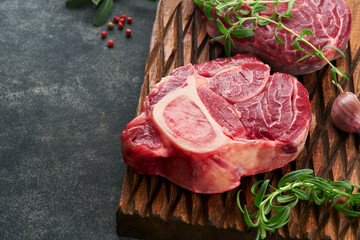 Osso Buco raw steak meat. Barbecue meat. Raw fresh cross cut veal shank and seasonings pepper, rosemary, thyme and salt on old wooden rustic background. Beef Leg Slice with marrow. Italian menu.