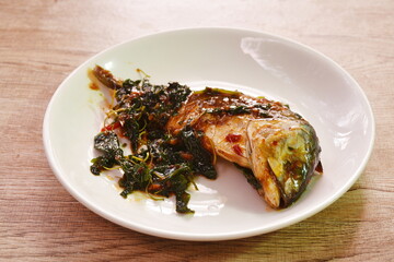 spicy boiled mackerel topping basil in chili sauce on plate 