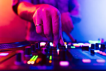 Close up of DJ hands on dj console mixer during concert in the club