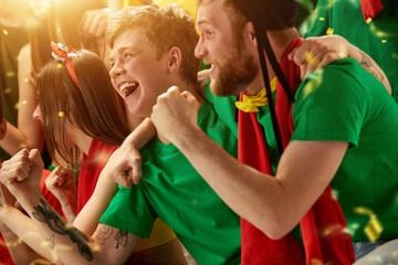 Winning game. Young people, portugal football fans emotionally watching match, supporting team at stadium during game. Concept of sport, competition, championship, emotions, hobby and entertainment