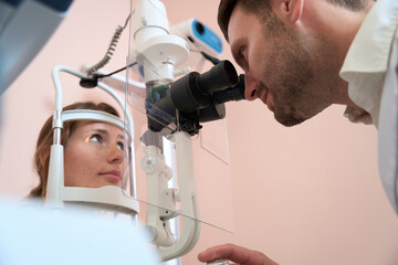 Caucasian lady receiving qualified examining her eyesight in optometrist office