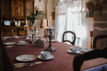 Ein gedeckter Tisch mit Kerzenständern und Teetassen steht in einem elegant eingerichteten Vintage-Raum
