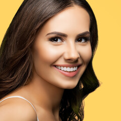 Fototapeta premium Portrait of smiling beautiful woman in white casual tank top looking at camera, isolated on yellow background. Brunette girl at studio concept. Square composition.