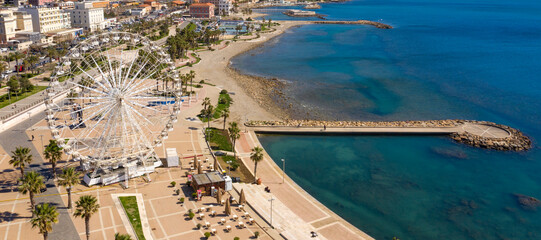 Aerial view of the Ferris wheel located on the waterfront of Civitavecchia in the Metropolitan City of Rome, Italy. On the city's waterfront there is a park, residential buildings and an empty beach.