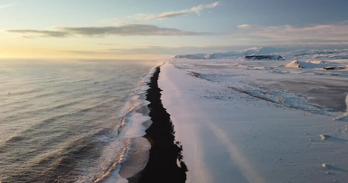 View at sunset of Kirkjufjara black sand beach from the Dyrholaey Promontory during winter in the south of Iceland.