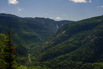 Fototapeta premium Landscape photography at Acropole des Draveurs, Quebec, Canada. Valley with hills and a river, pine trees and blue sky with white clouds