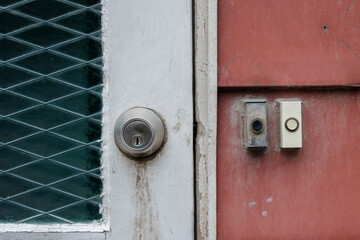 Doorbell and door lock, white door and red facade, old building