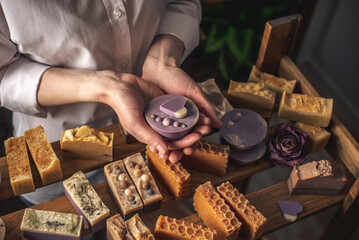 Woman master soap maker holds handmade lavender soap in her hands. Eco-friendly natural craft cosmetics production