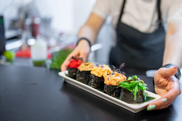 professional chef's hands making gunkan sushi roll in a restaurant kitchen
