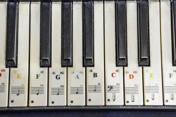 Black and white piano keys with music stickers very close