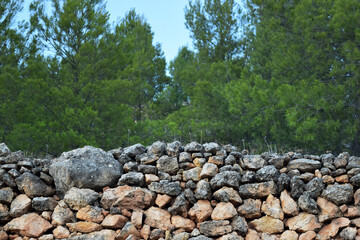 Close up view of an old stone wall of stacked rocks in a forest or country place. Agricultural terrace