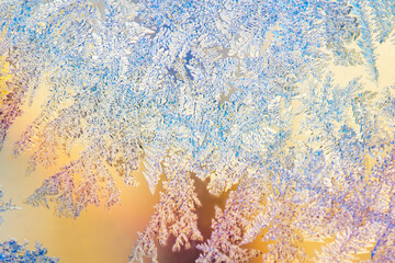 Frosty frost on a glass window. Close-up of colorful ice patterns lightly blurred in soft focus.