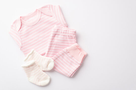 Baby shower concept. Top view photo of pink infant clothes shirt pants and socks on isolated white background