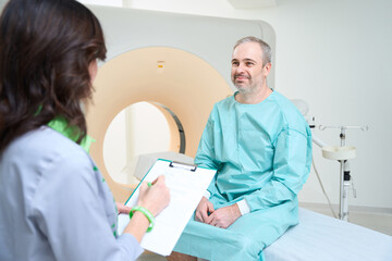 Obraz premium Doctor filling out a patient questionnaire before CT diagnostic procedure