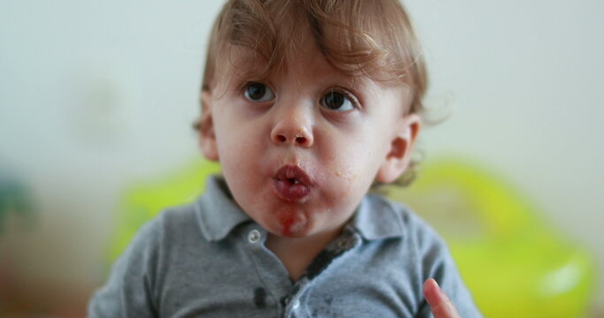 Cute One Year Old Baby Eating Food. Portrait Infant Toddler With Mouth Full Chewing