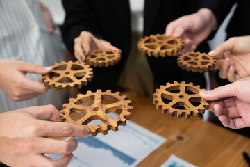 Closeup top view businesspeople hand holding gear and join together over meeting table with...