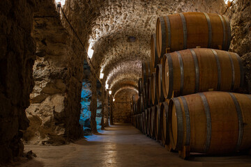 Naklejka premium Underground brick and stone cellar with wooden barrels for storing malbec and tannat