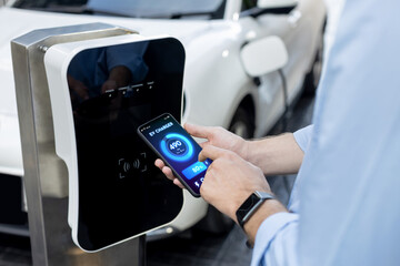Closeup progressive businessman look at EV car's battery status application on smart phone screen...