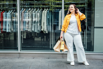 Size-inclusive body positivity advocates for acceptance and celebration of all body sizes and shapes, including plus-size or overweight. Happy curvy young woman in yellow cloth on city street