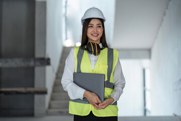 Portrait smiling female engineer with laptop at construction site