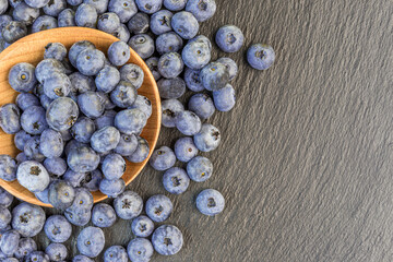 Blueberry in a rustic wooden spoon on a stone background with copy space.