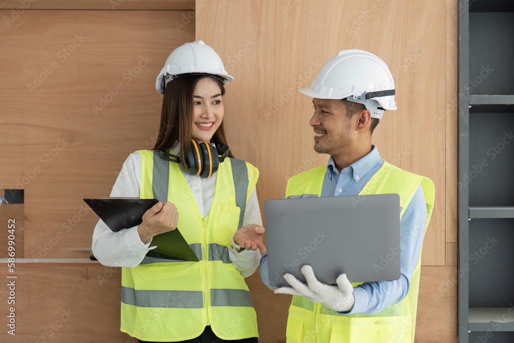 Poster engineer construction and in vest with helmet working with laptop, standing on building construction