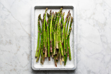 Green  Raw Asparagus  on a Baking Sheet on Marble background