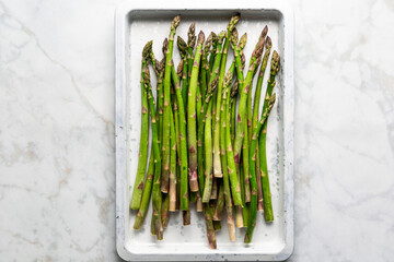 Green  Raw Asparagus  on a Baking Sheet on Marble background