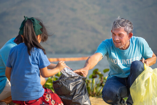 A Senior Man Volunteers Help Children Collect And Separate Plastic Bottle At The Sand Beach ,concept Raising Children For Volunteering Awareness Environmental Conservation