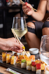 Mujeres y manos femeninas comiendo sushi en un restaurant con vajill rustica