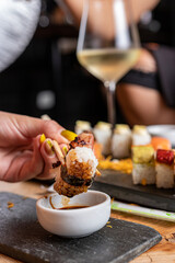 Mujeres y manos femeninas comiendo sushi en un restaurant con vajill rustica