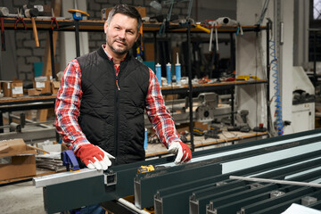 Smiling male working in protective gloves in the workshop