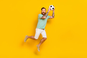 Fototapeta na wymiar Full length body photo of young overjoyed energetic professional football player guy sporty catch sphere isolated on yellow color background