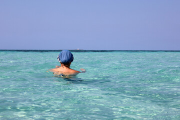 Woman in sun hat swimming in azure sea water. Beach vacation on Caribbean islands