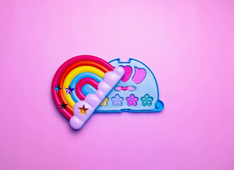 Children's set of decorative cosmetics for a little girl in the shape of a rainbow. Flat lay.