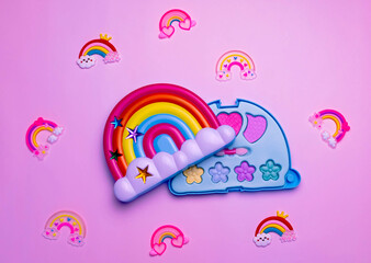 Children's set of decorative cosmetics for a little girl in the shape of a rainbow. Flat lay.