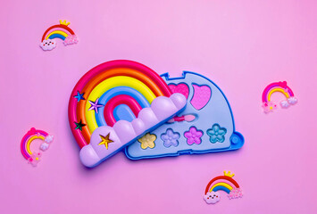Children's set of decorative cosmetics for a little girl in the shape of a rainbow. Flat lay.