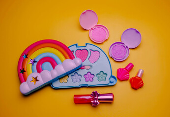 Children's set of decorative cosmetics for a little girl in the shape of a rainbow. Flat lay.