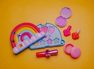Children's set of decorative cosmetics for a little girl in the shape of a rainbow. Flat lay.