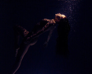 Underwater shoot of beautiful woman swimming and relaxing in water in sunbeams.