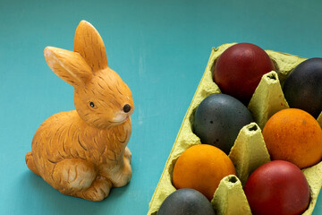 Eggs colored in organic dyes (onion skin, turmeric, red cabbage) and Easter bunny on a table.