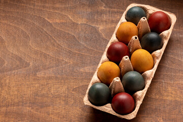 Colorful eggs in egg storage box. Eggs colored in organic dyes (onion skin, turmeric, red cabbage).